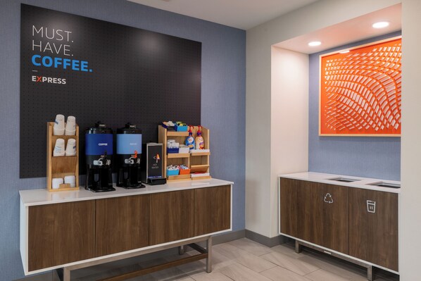 Una estación de café moderna con dispensadores de café de la marca, un enfriador de agua y un contenedor para reciclaje.