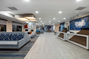 Un moderno vestíbulo de hotel con mostrador de recepción, zona de estar y comedor.