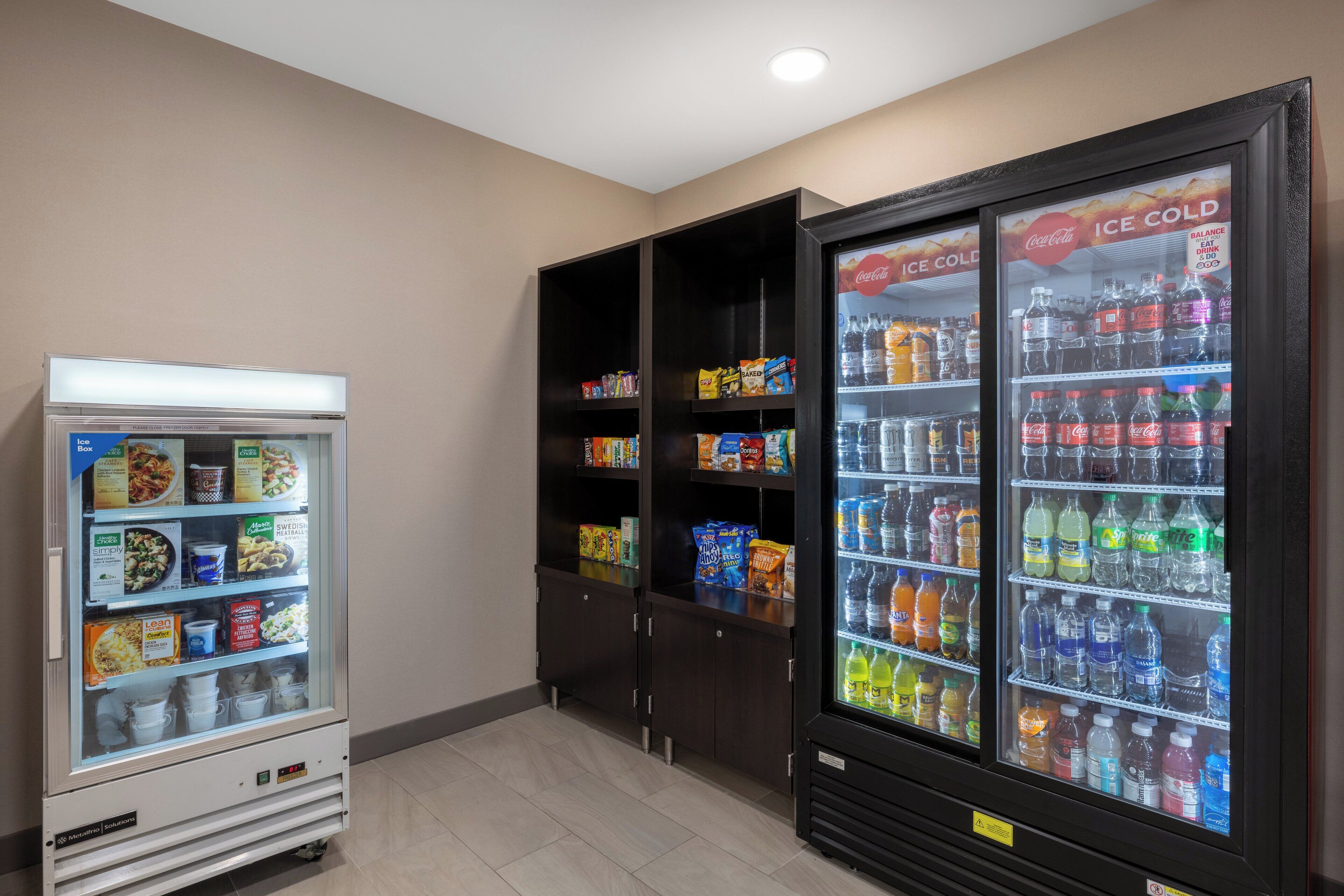 A vending machine and two ice cold beverage dispensers in a room.