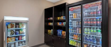 A vending machine and two ice cold beverage dispensers in a room.