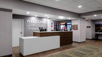 A reception desk with a 'Welcome to the Mother of State' sign, a vending machine, and directional signs for hotel amenities.