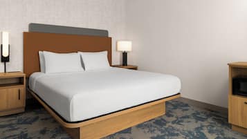 A hotel room with a bed, bedside tables, a lamp, and a microwave.