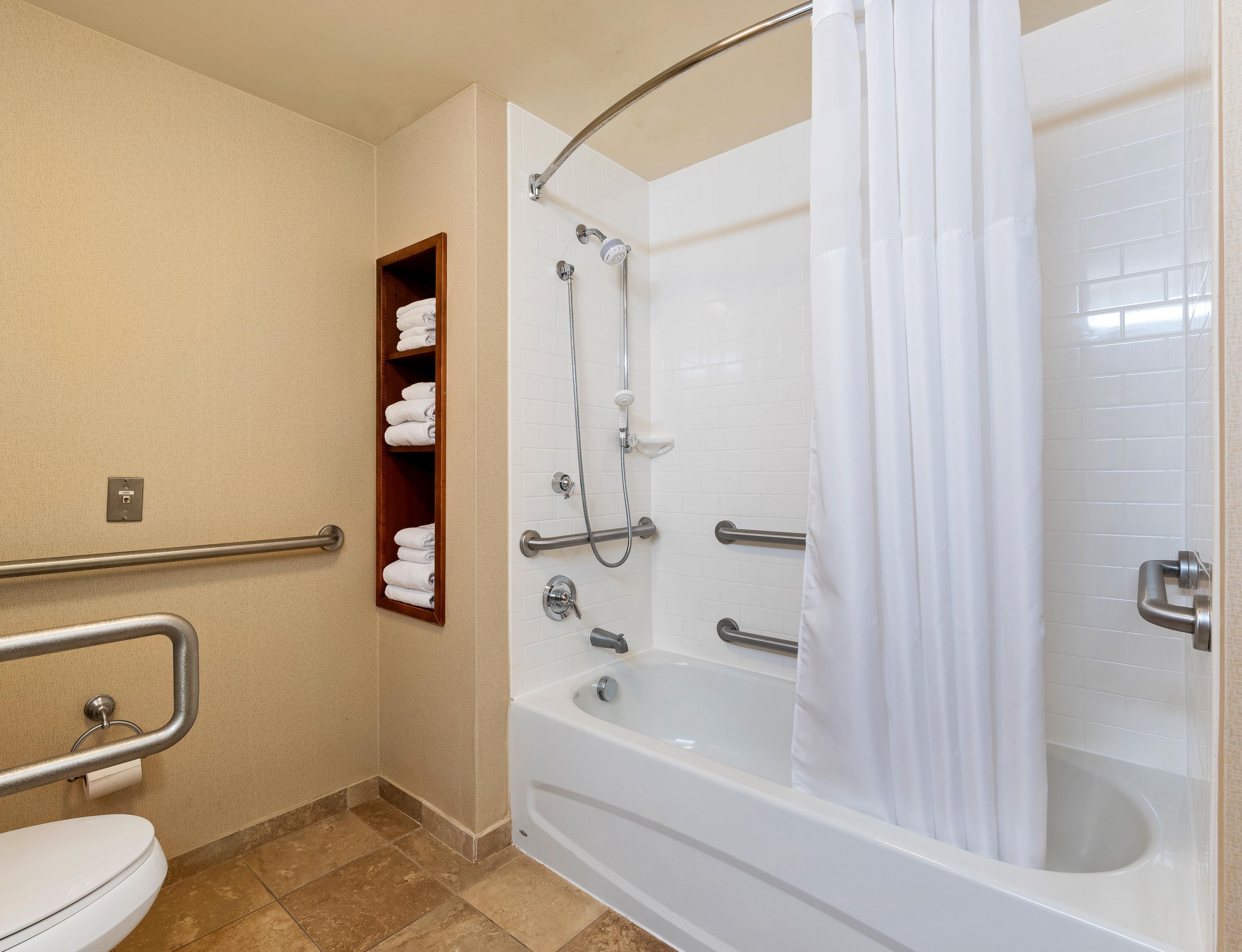 A bathroom with a white bathtub, a shower with a glass door, a toilet, and a towel rack.