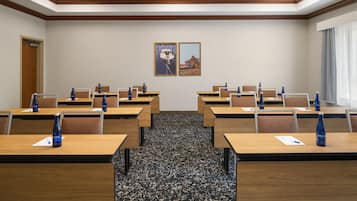 A conference room with multiple tables, chairs, and water bottles.
