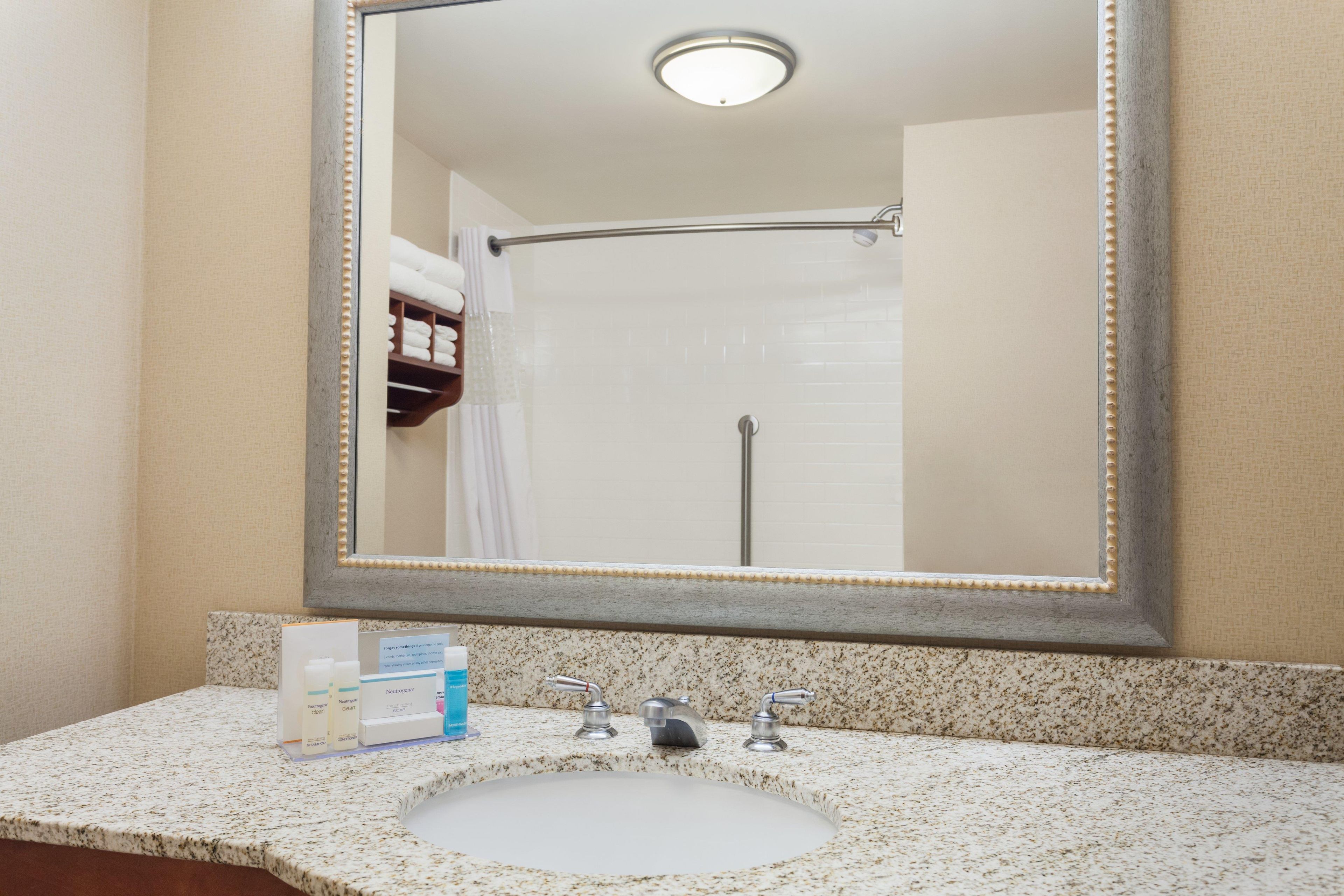 Un bagno con uno specchio grande, un lavandino e una doccia.