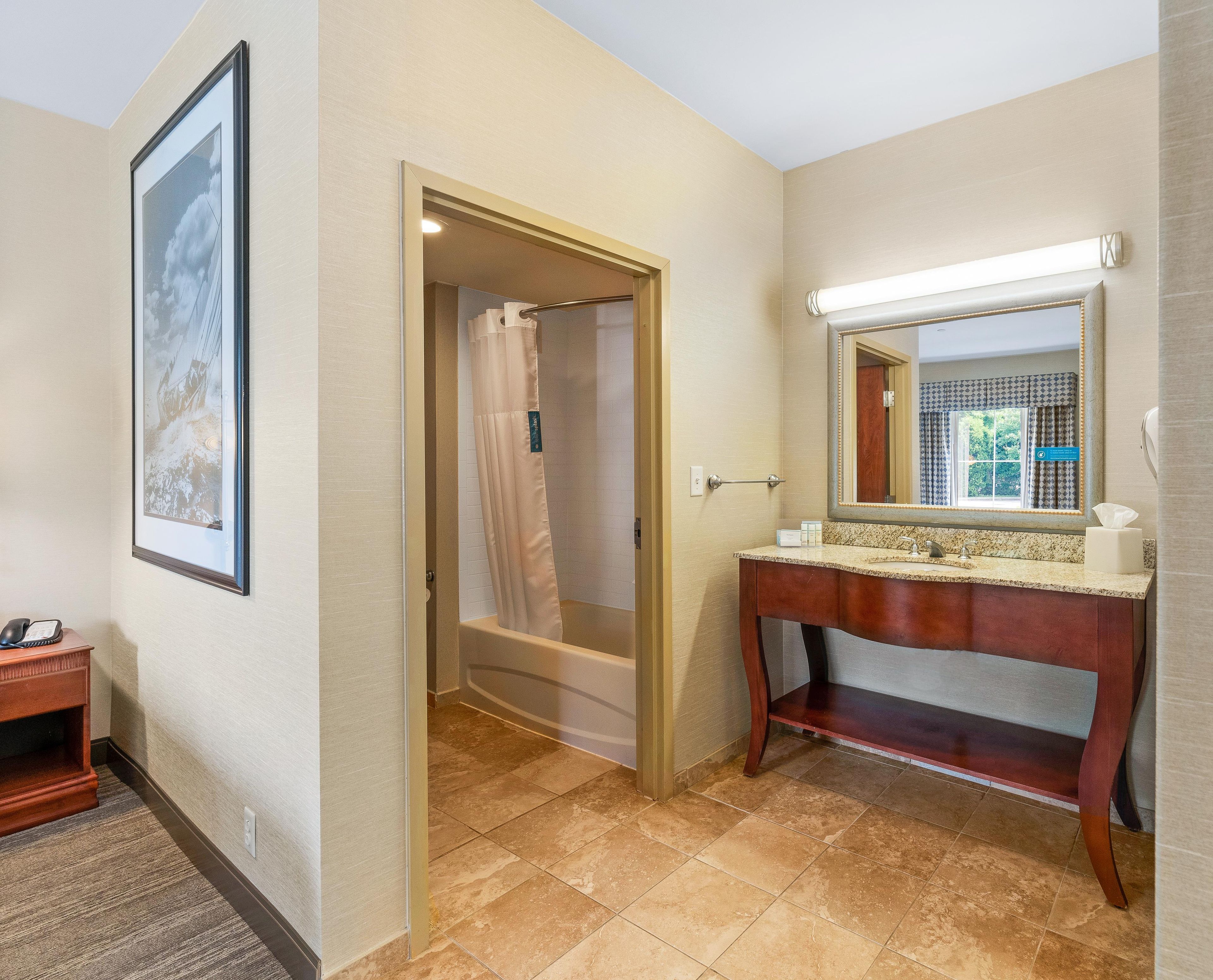 Une salle de bain avec une baignoire, un meuble-lavabo avec un miroir et un tableau encadré au mur.