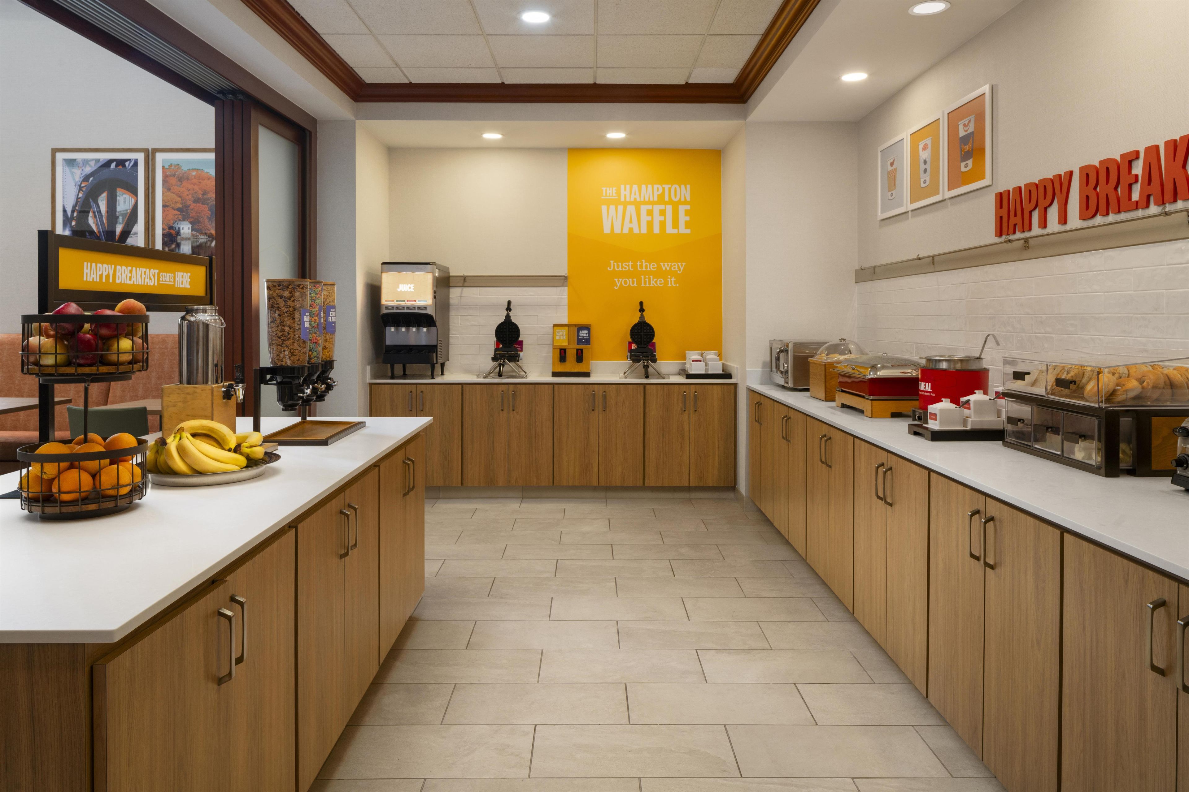 A modern kitchen with a central island, a coffee machine, and a waffle station.