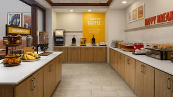 A modern kitchen with a central island, a coffee machine, and a waffle station.