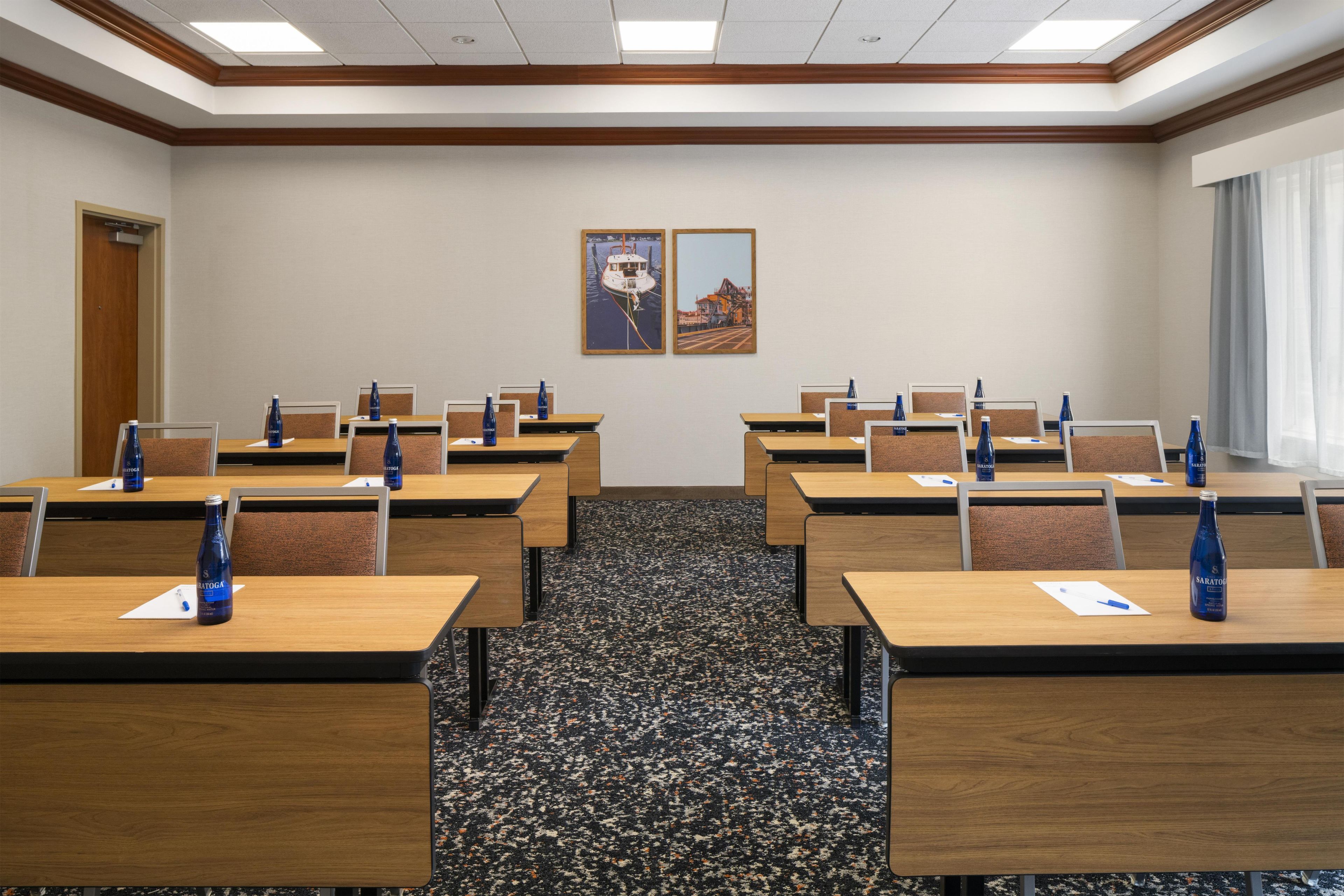 Uma sala de conferências com várias mesas, cadeiras e garrafas de água.