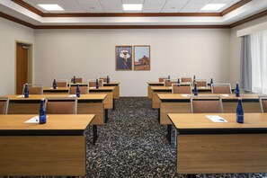 Uma sala de conferências com várias mesas, cadeiras e garrafas de água.