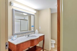 A bathroom with a large mirror, a sink, and a toilet.