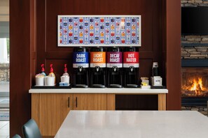 A coffee station with four dispensers labeled DARK ROAST, LIGHT ROAST, DECAF ROAST, and HOT WATER. - Hampton Inn & Suites Mystic (Mystic)