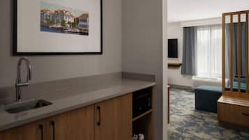 A modern kitchen with a sink, cabinets, and a framed picture on the wall.