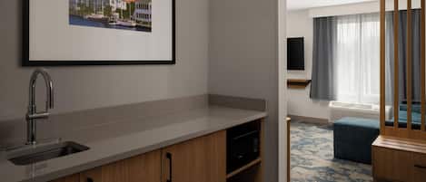 A modern kitchen with a sink, cabinets, and a framed picture on the wall.