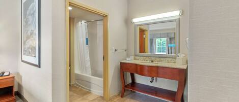 A bathroom with a wooden vanity, a large mirror, and a shower area.
