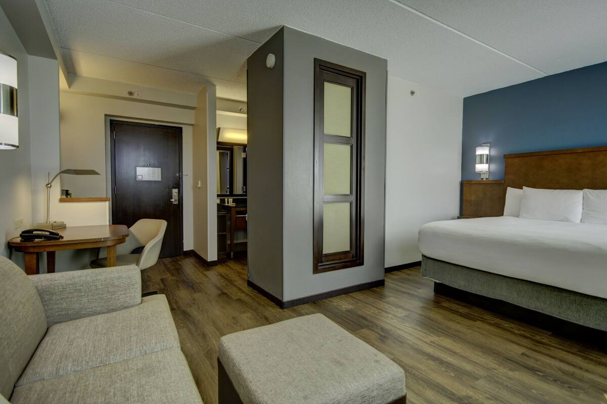 Une chambre d’hôtel avec un lit, un bureau, une chaise et une petite table.