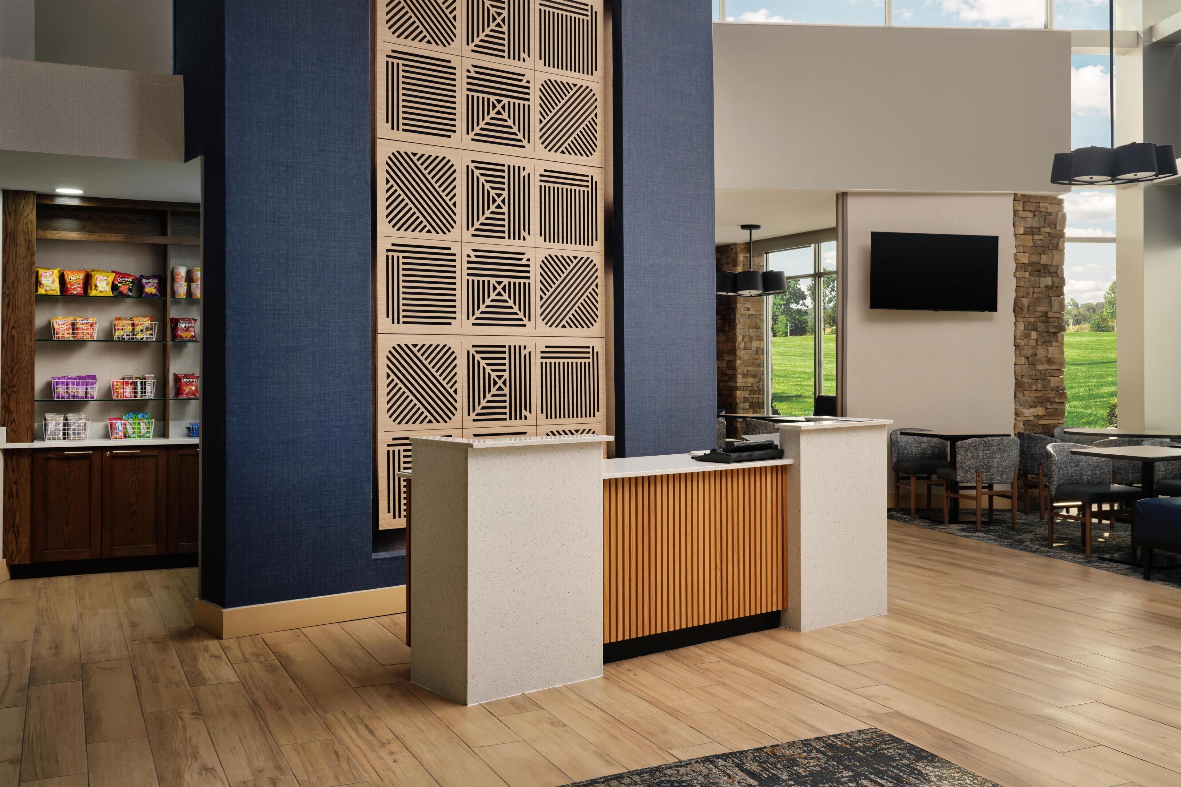 Un área de recepción con un mostrador de madera, un papel tapiz estampado y vistas al exterior.