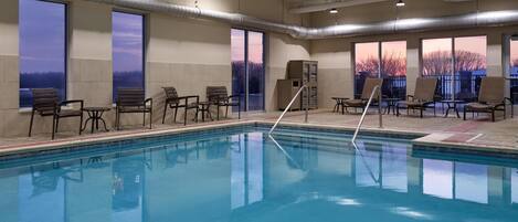 A swimming pool with chairs and a view of the sunset.