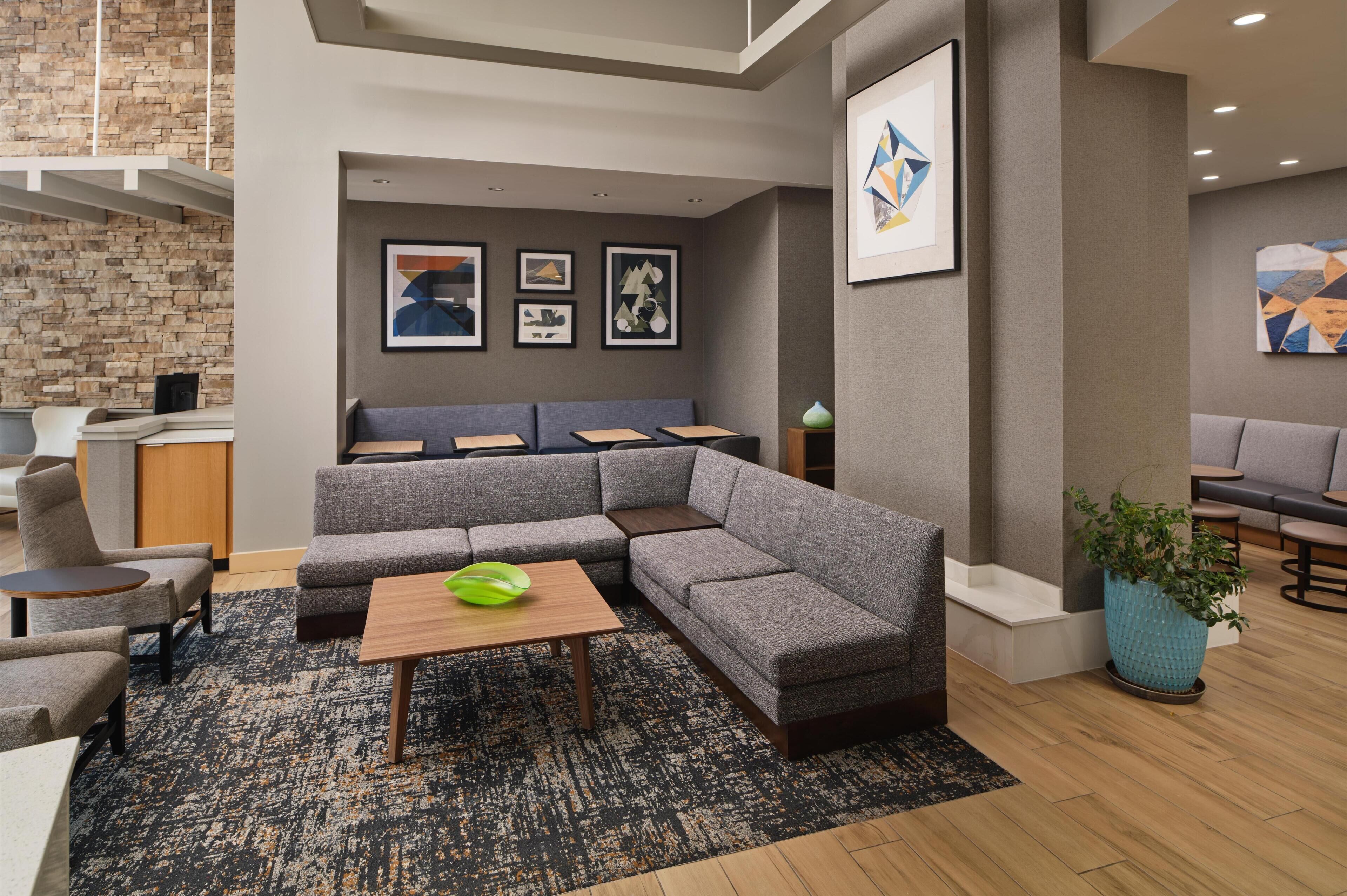 A modern lounge area with a sectional sofa, a coffee table, and a potted plant.