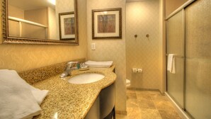 A bathroom with a granite countertop sink, a large mirror, framed artwork on the wall, and a glass shower enclosure. - Holiday Inn Express West Jefferson by IHG (West Jefferson)
