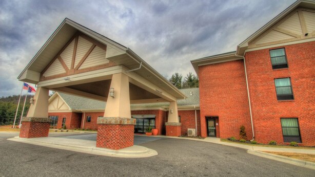 A brick building with a covered entrance and a flagpole. - Holiday Inn Express West Jefferson by IHG (West Jefferson)