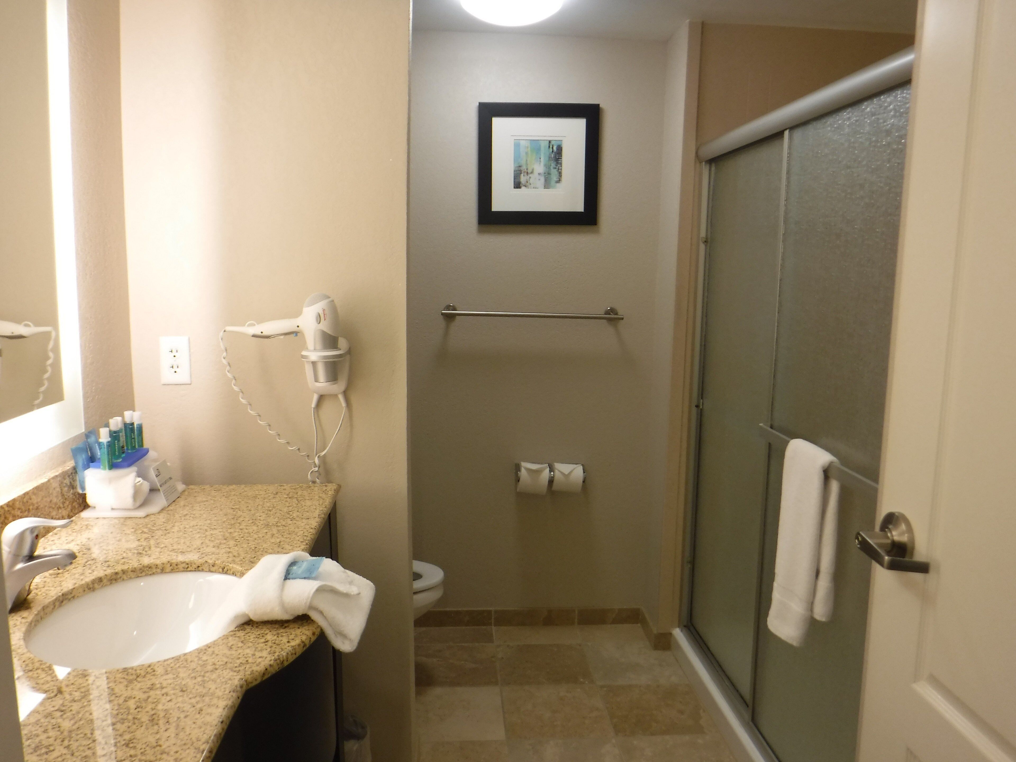 A bathroom with a sink, towel rack, toilet, and a framed picture on the wall.
