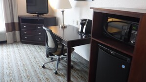 A hotel room with a desk, chair, television, lamp, microwave, and a small refrigerator. - Holiday Inn Express West Jefferson by IHG (West Jefferson)