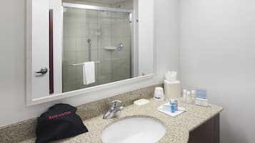 A bathroom with a sink, mirror, and shower.