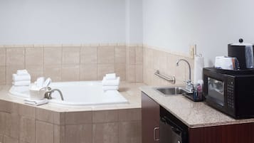 A bathroom with a bathtub, sink, and a microwave.