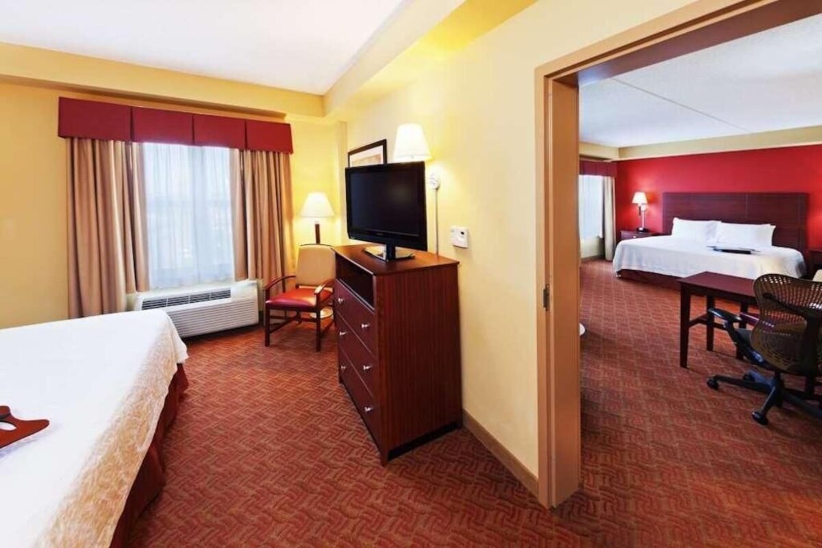 Ein Hotelzimmer mit einem Bett, einem Schreibtisch mit Computer, einem Sessel, einer Kommode und einem Fernseher.