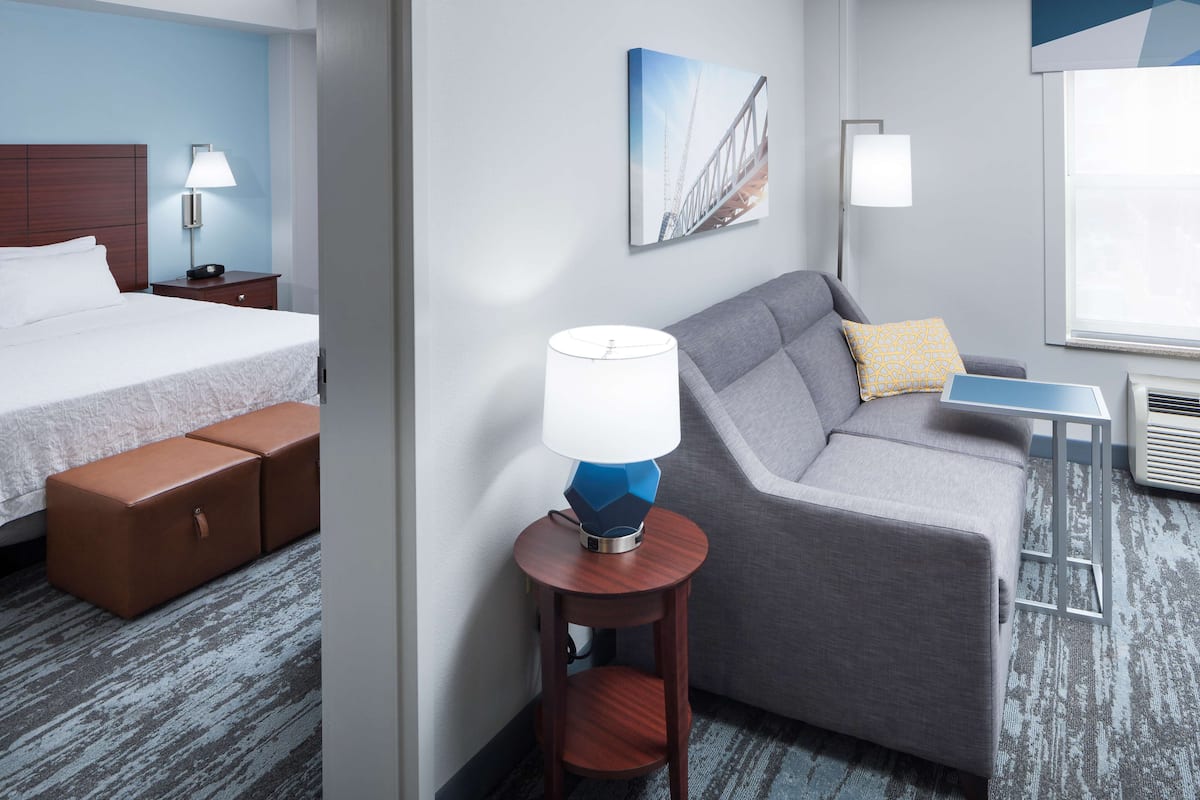 Ein Hotelzimmer mit Bett, Sofa, einem kleinen Tisch und einer Lampe.