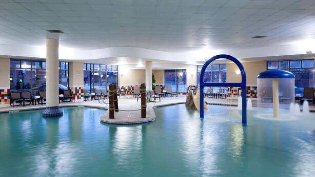 An indoor swimming pool with multiple seating areas and a central water feature.
