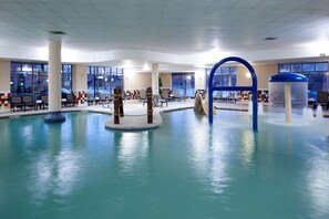 Une piscine intérieure dotée de plusieurs espaces de détente et d’un élément décoratif central aquatique.