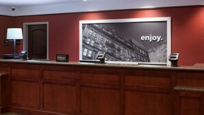 A hotel reception desk with a large poster of a building and the word "enjoy."