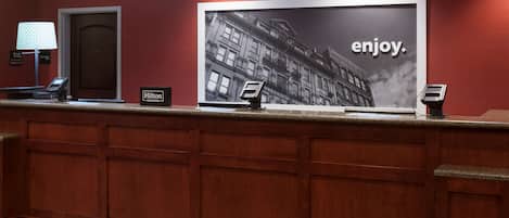 Un mostrador de recepción de hotel con un cartel grande de un edificio y la palabra 'enjoy'.