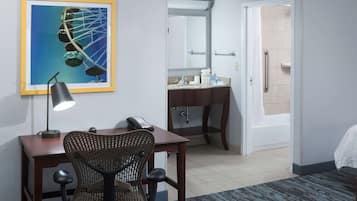 A hotel room with a desk, chair, and a large mirror.