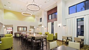 A hotel lobby with a large dining area, multiple chairs, a long table, and a chandelier. - Hampton Inn & Suites by Hilton Walla Walla (Walla Walla)