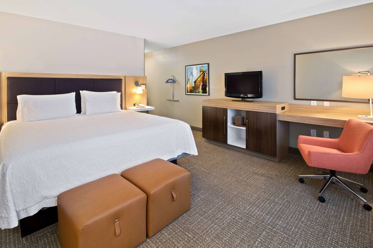 A hotel room with a bed, a desk with a computer, a television, and a chair.