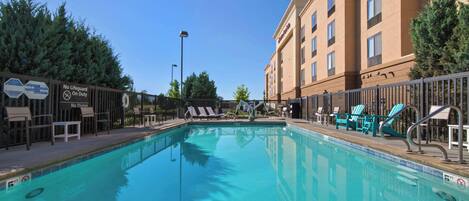 A swimming pool with lounge chairs and a lifeguard sign.