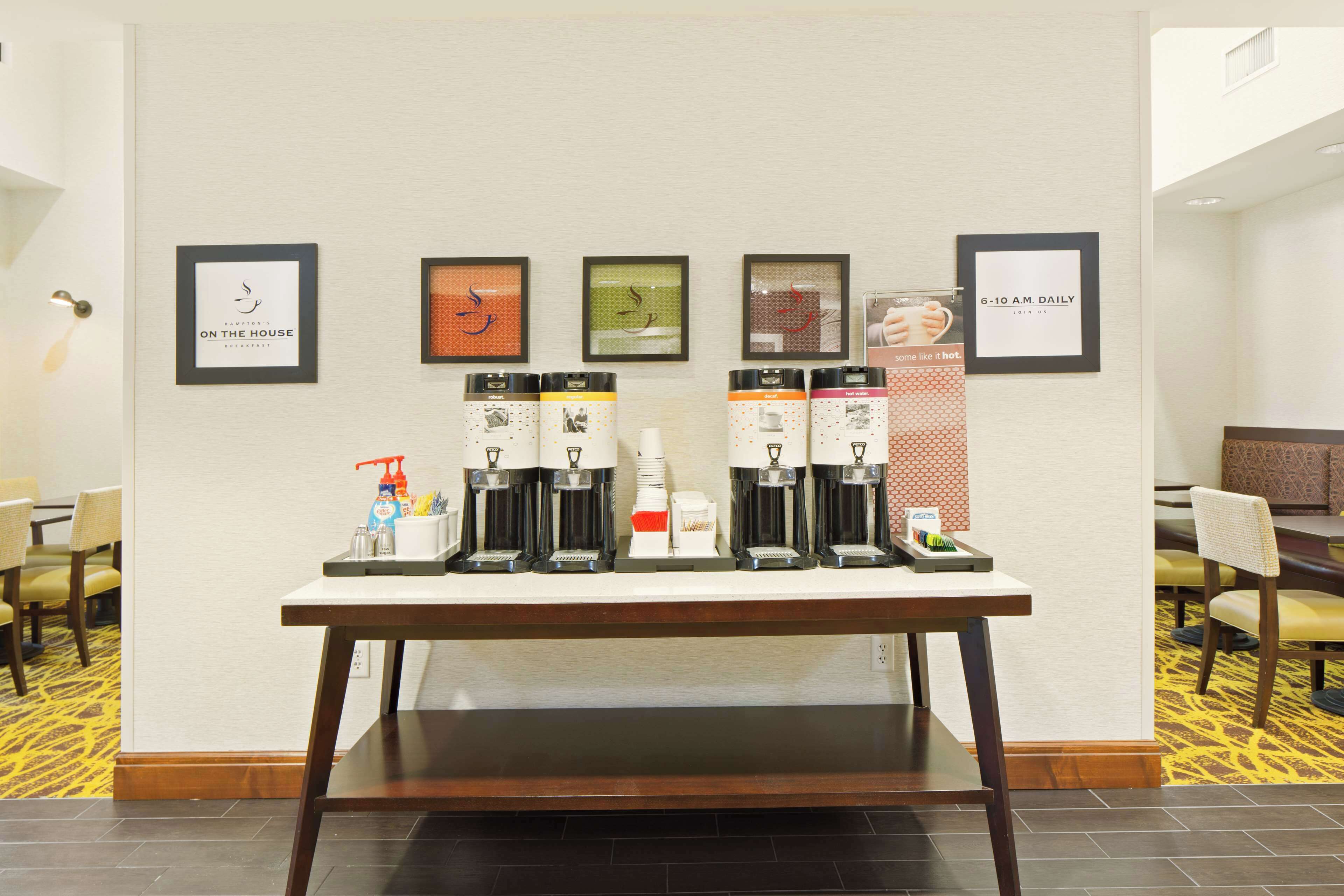 A coffee station with multiple coffee makers and a framed sign on the wall.