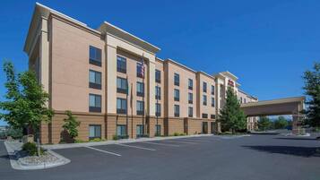 A multi-story hotel with a flat roof, a parking lot, and a covered walkway.