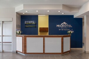 Un mostrador de recepción con una pared azul, una encimera de madera y un cartel que dice 'MICROTEL INN & SUITES BY WYNDHAM'.