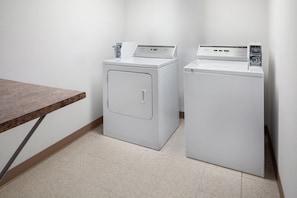 A laundry room with two white washing machines and a wooden table.
