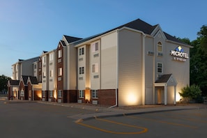 A multi-story hotel with a sign reading 'MICROTEL BY WYNDHAM,' featuring a brick facade, multiple windows, and a parking lot.