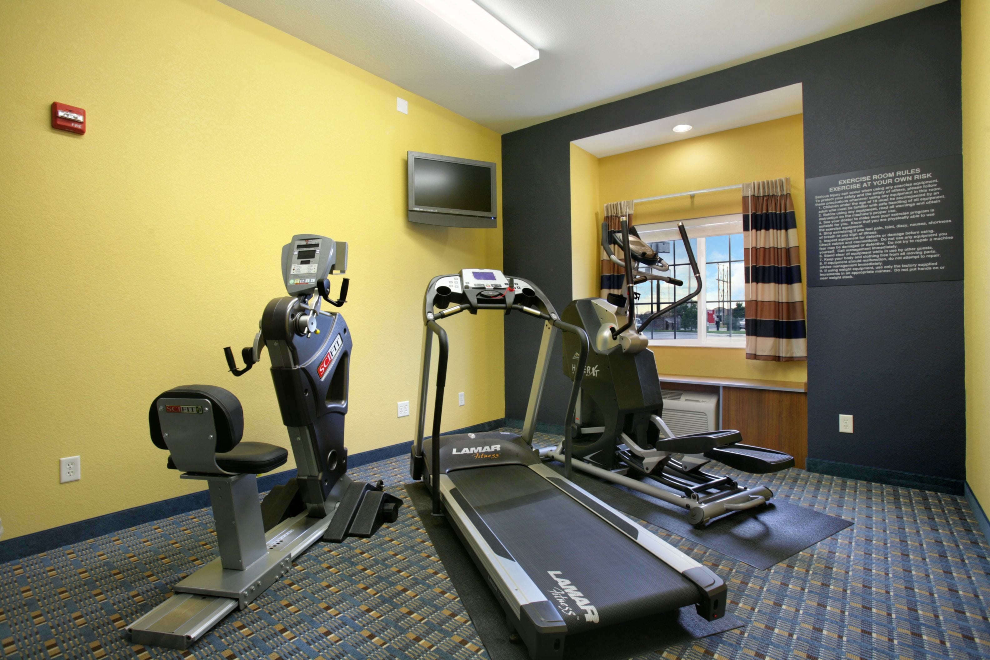 A hotel fitness room with a treadmill, elliptical, and stationary bike.