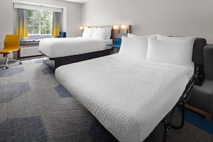 Habitación de hotel con dos camas, un escritorio, una silla y una ventana con cortinas.
