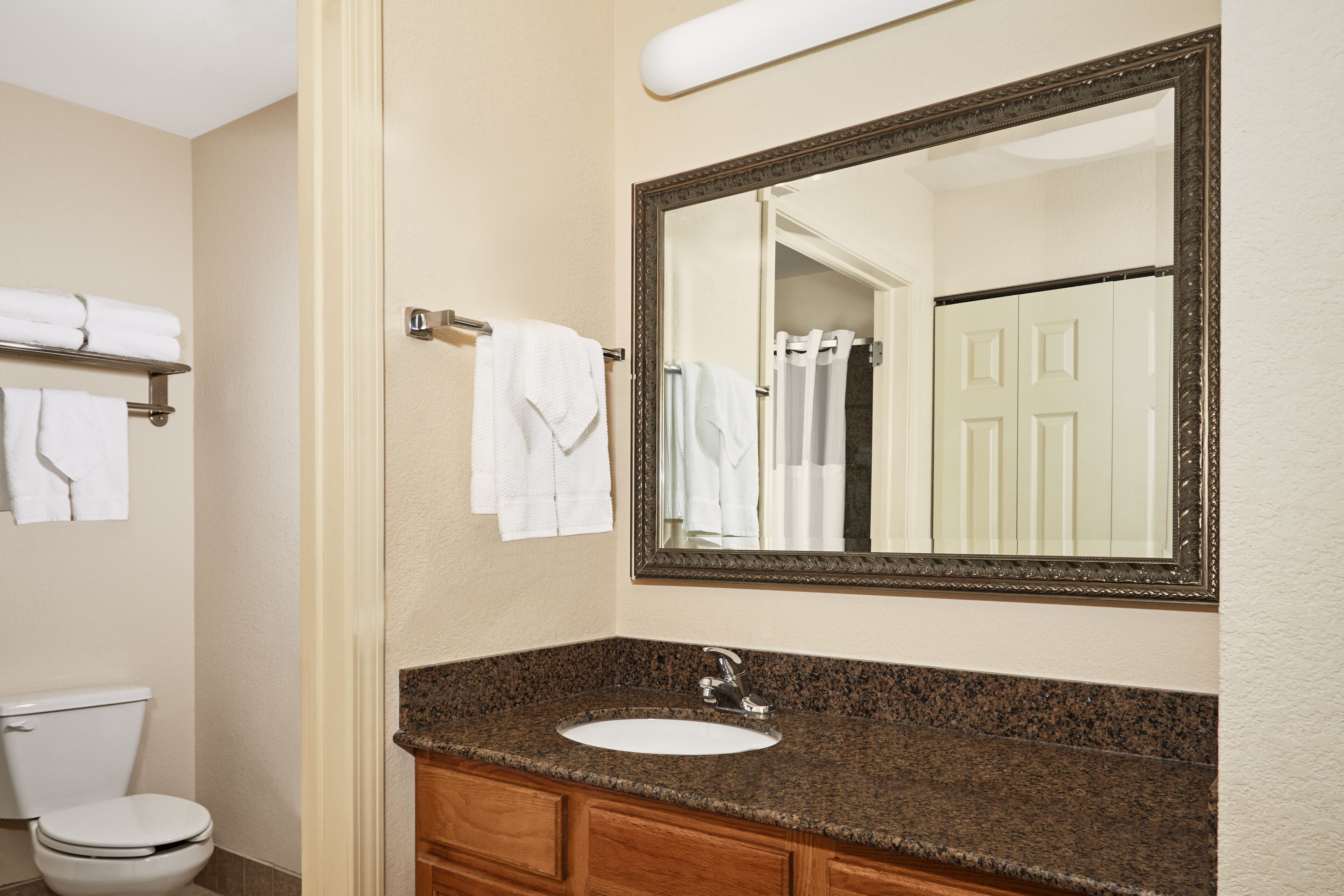 A bathroom with a sink, mirror, towel rack, and toilet.