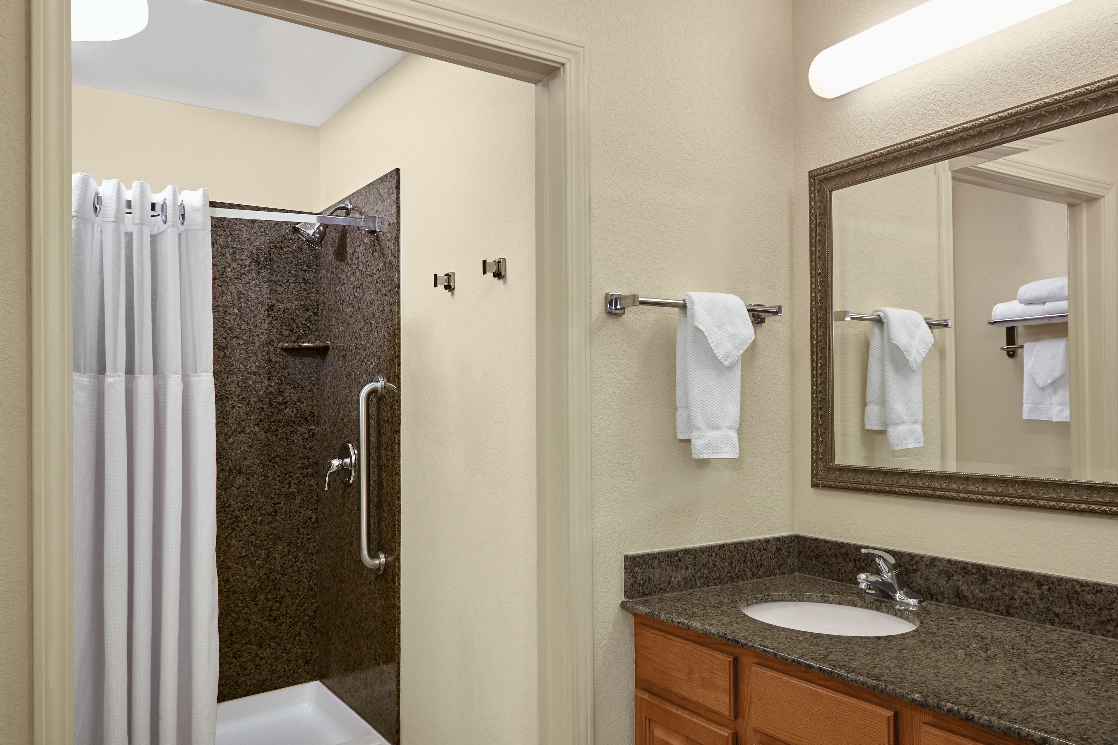 A bathroom with a shower, a sink, and a mirror.