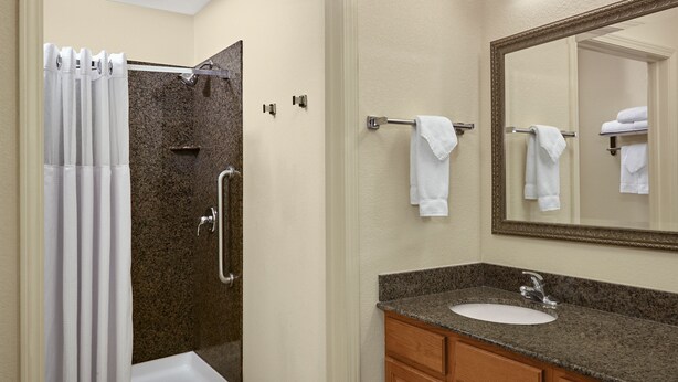 Une salle de bain avec une douche, un lavabo et un miroir.