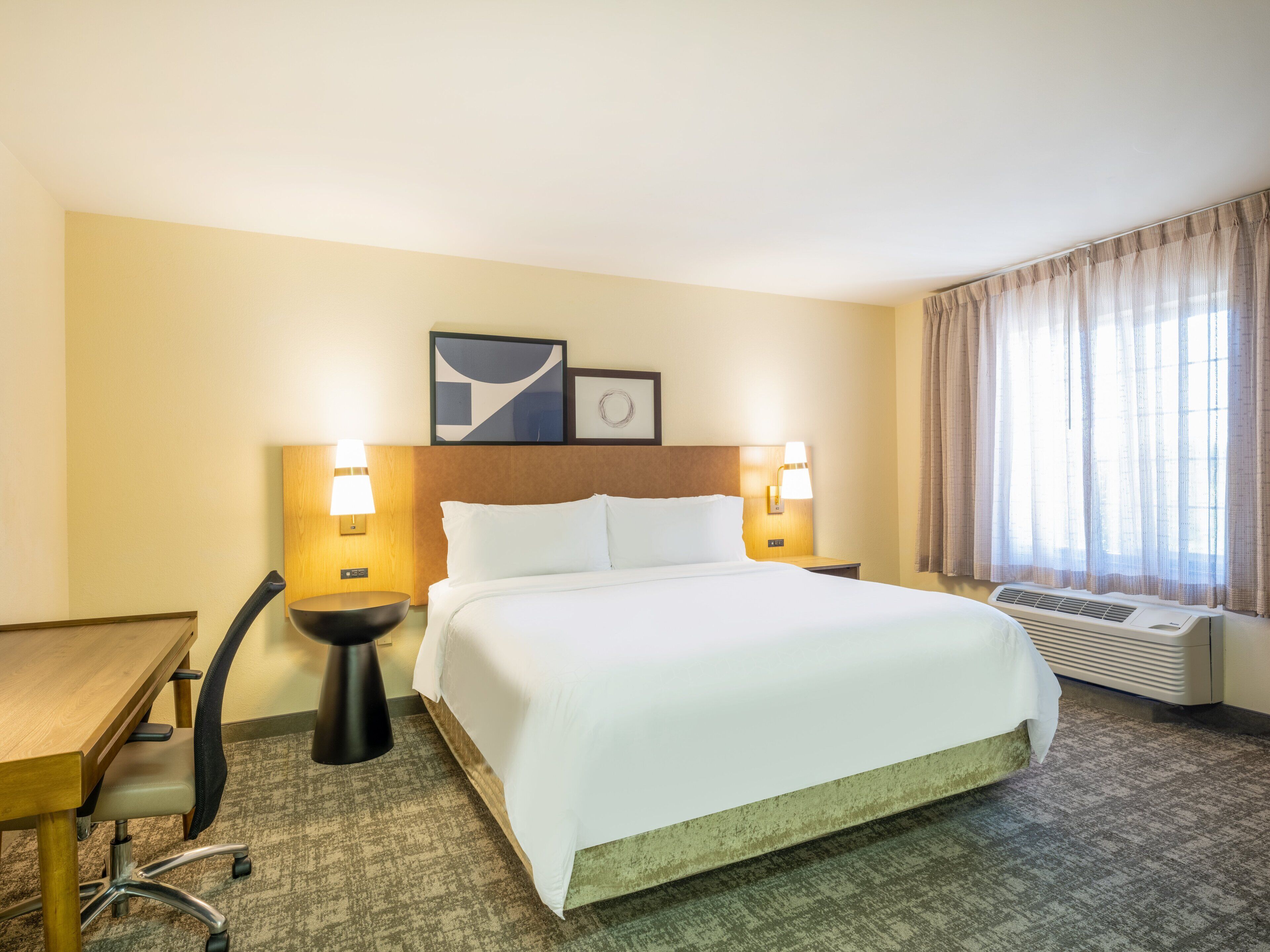 Ein Hotelzimmer mit einem Bett, zwei Nachttischlampen, einem Schreibtisch und einem Sessel.